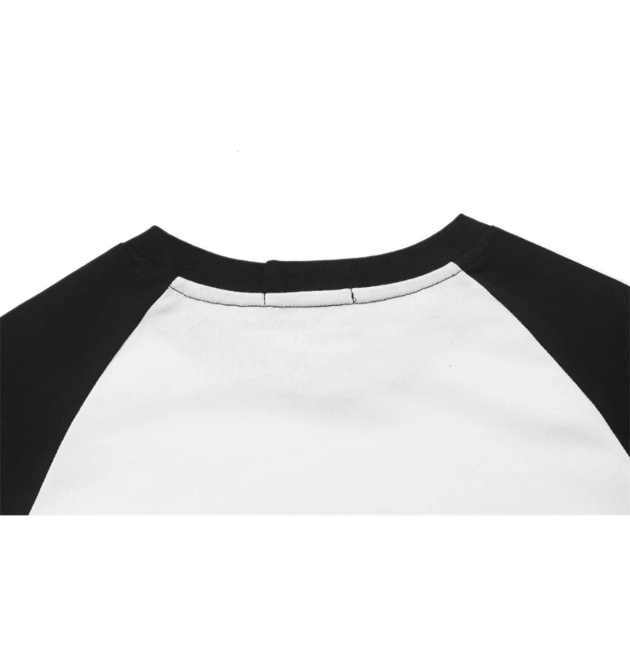 Close-up of a raglan-style baseball shirt showing a white body and black sleeves against a plain white background.